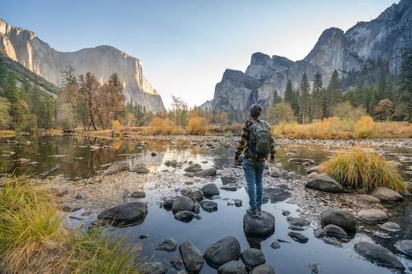 A hiker crossing a stream in a mountain valley