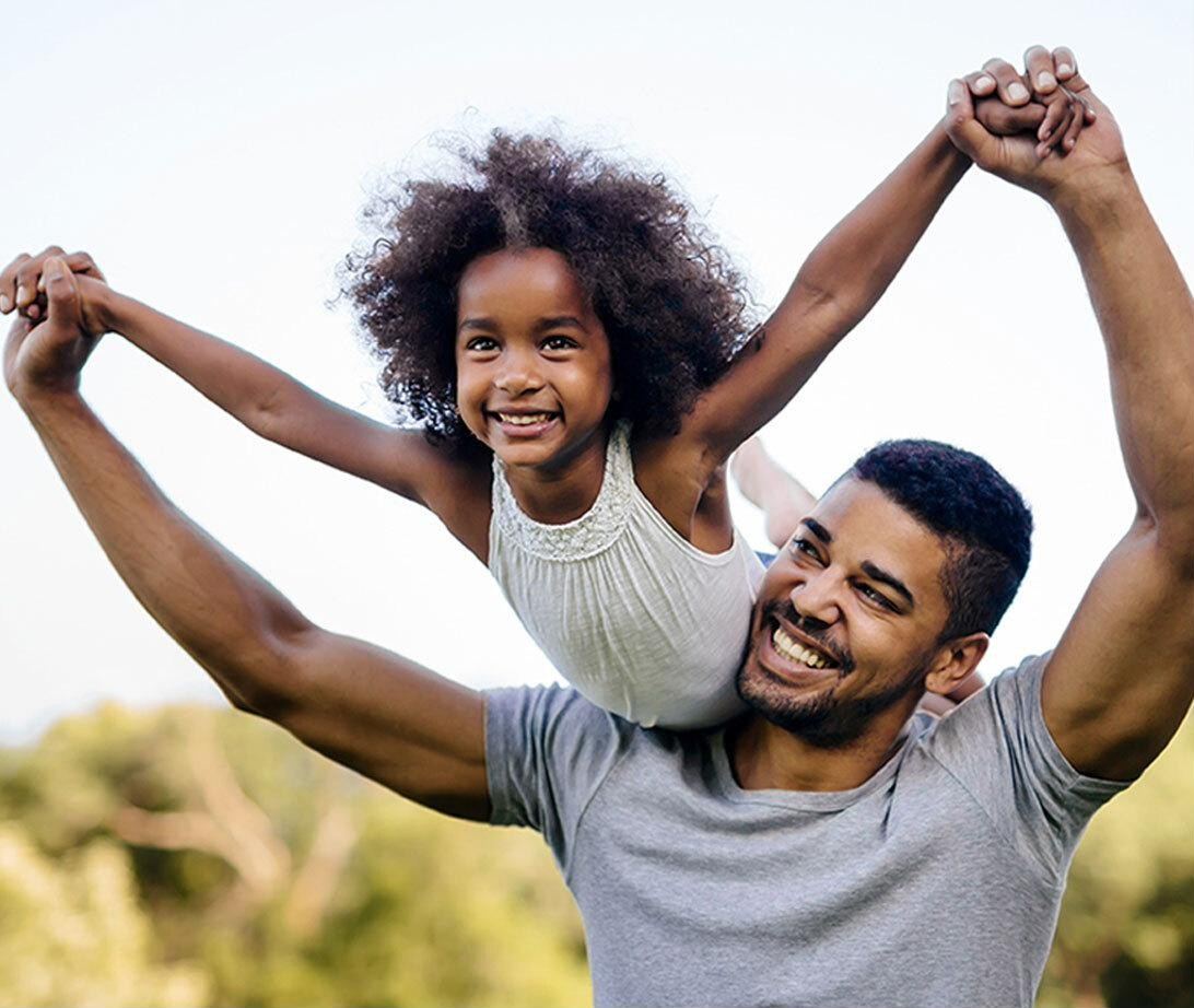 A father lifting his smiling daughter outdoors